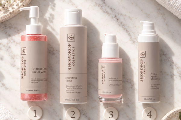 ShopDrop Cosmetics 4-step women's skincare routine flat lay on marble — Radiant Glow Facial Wash, Hydrating Toner, Exosome Serum, Peptide Ageless Cream